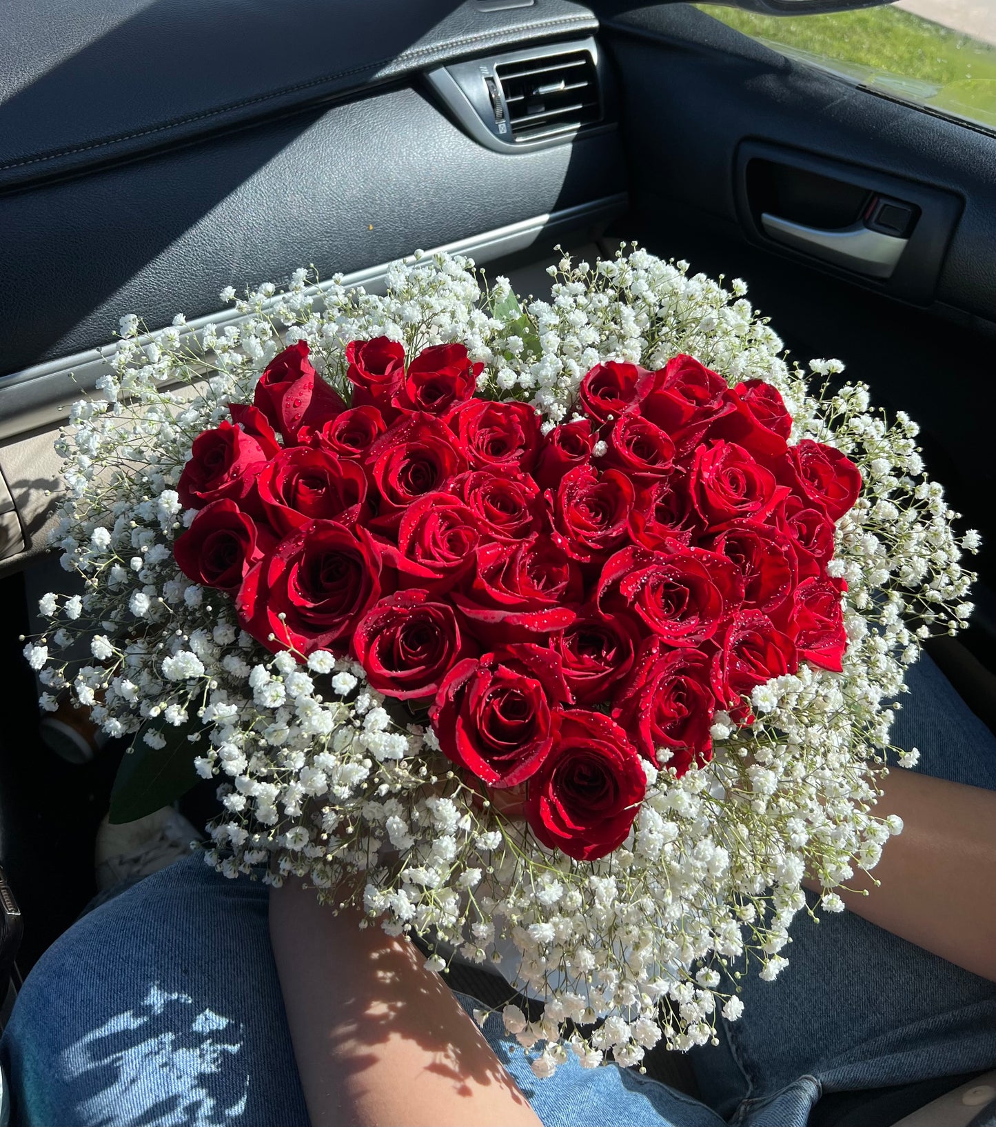A heart-shaped arrangement of red roses with white filler flowers, presumably meant as a romantic gift.