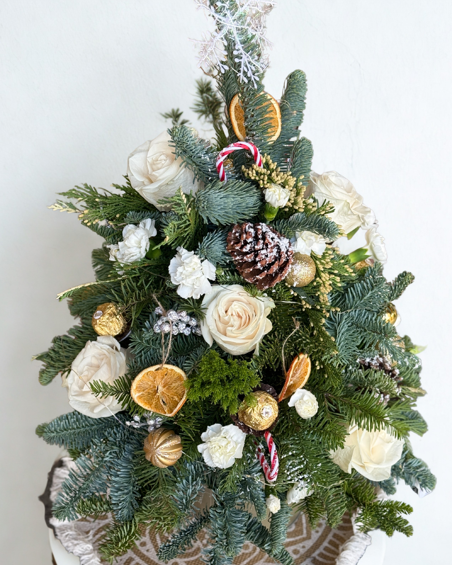 Fresh Christmas Tree arrangement The Floristry’s Snowy Oasis Tree features white roses, seasonal white blooms and fillers, paired with fresh holiday greens.