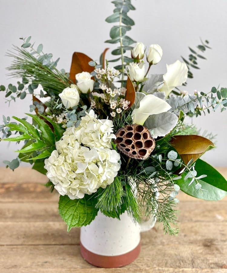 White Snowy Christmas Arrangement with white roses, silvery eucalyptus, and festive greenery.