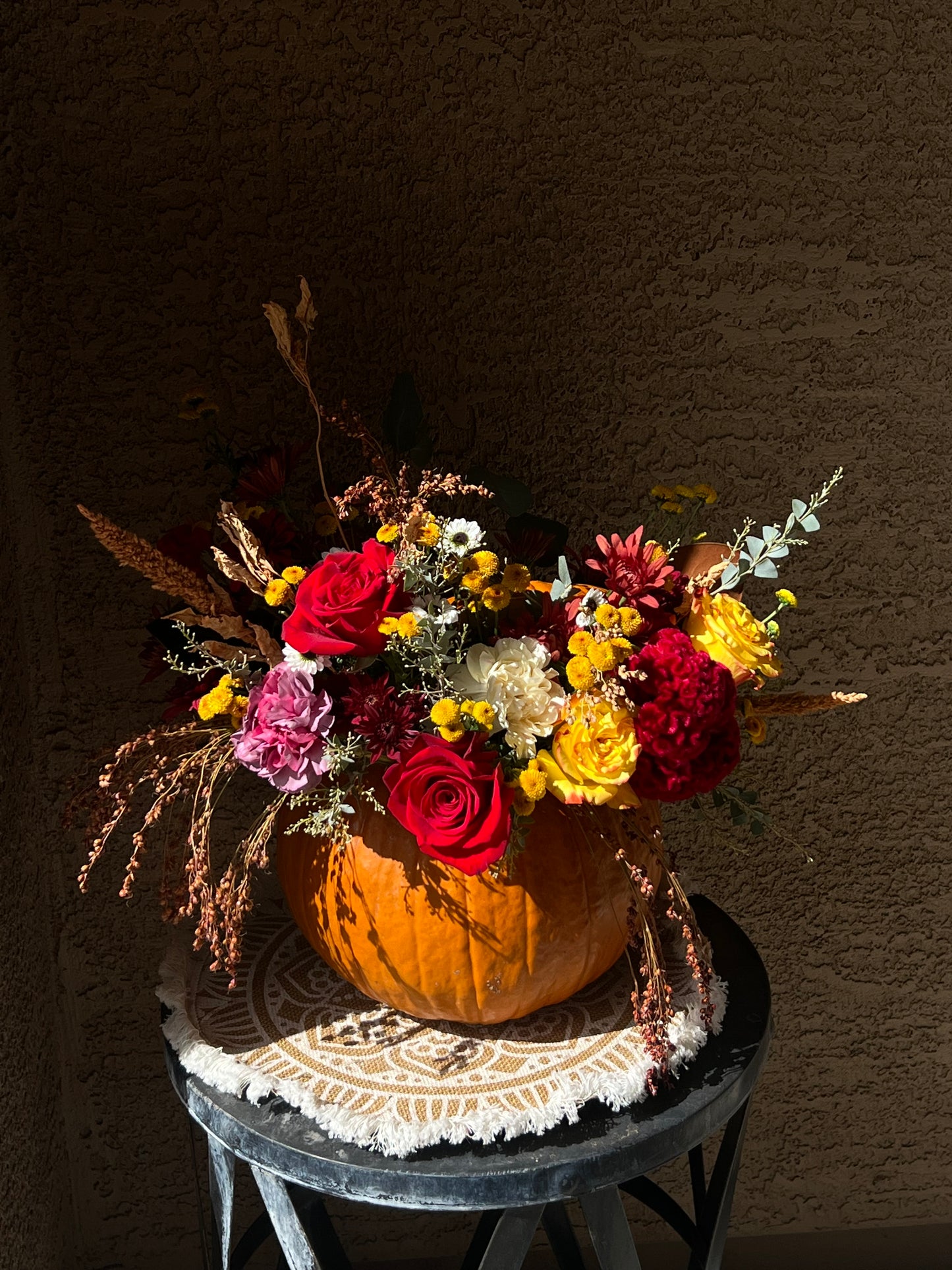 Surprised Pumpkin Centerpiece featuring fresh flowers and preserved decorations arranged inside a unique pumpkin. Available in standard, deluxe, and premium sizes with varying flower stems and higher-value blooms.