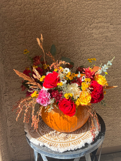Surprised Pumpkin Centerpiece featuring fresh flowers and preserved decorations arranged inside a unique pumpkin. Available in standard, deluxe, and premium sizes with varying flower stems and higher-value blooms.