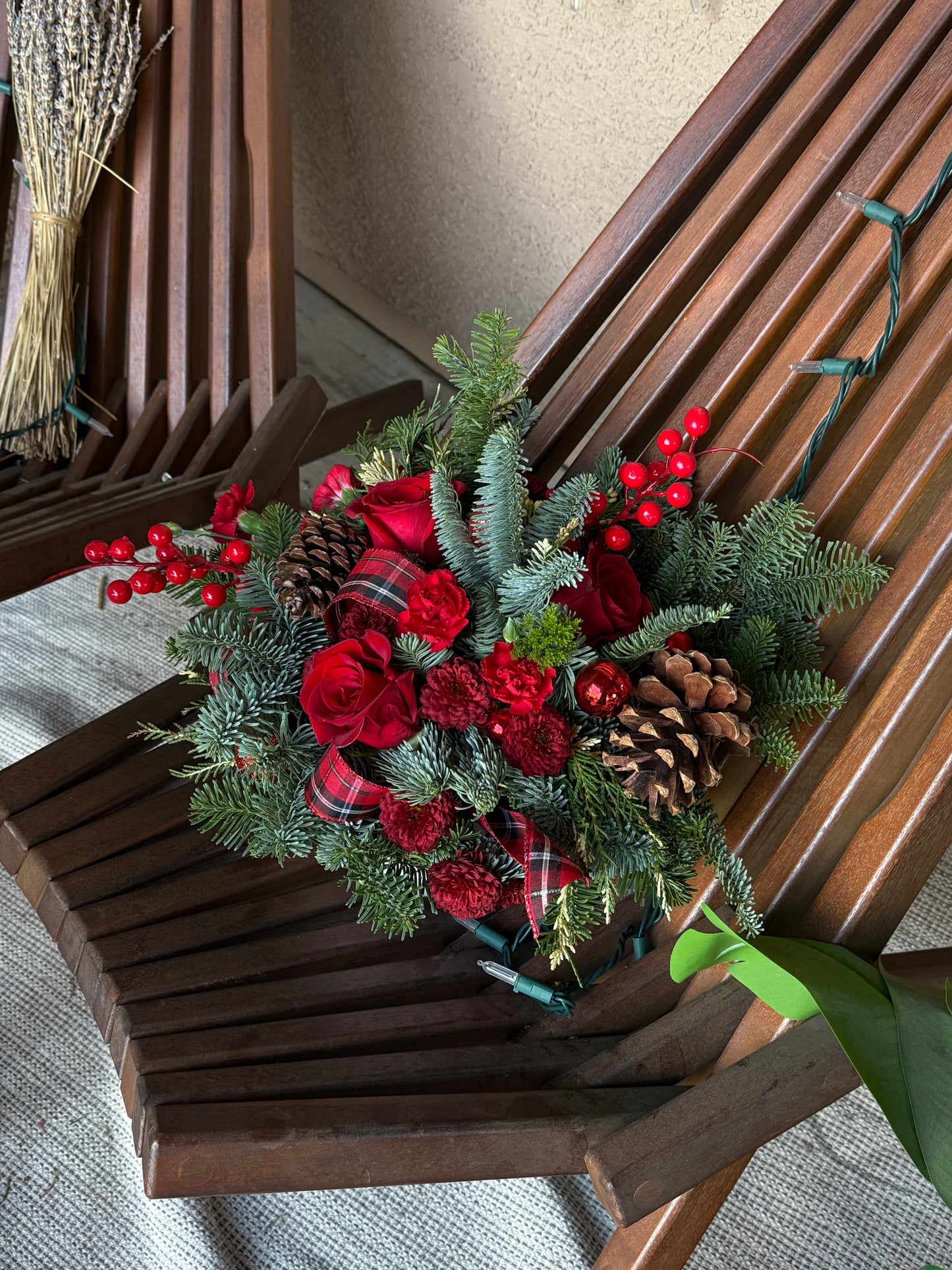 Mid-size festive red holiday centerpiece with noble fir, cedar, white pine, pinecones, and red berries on a dining table