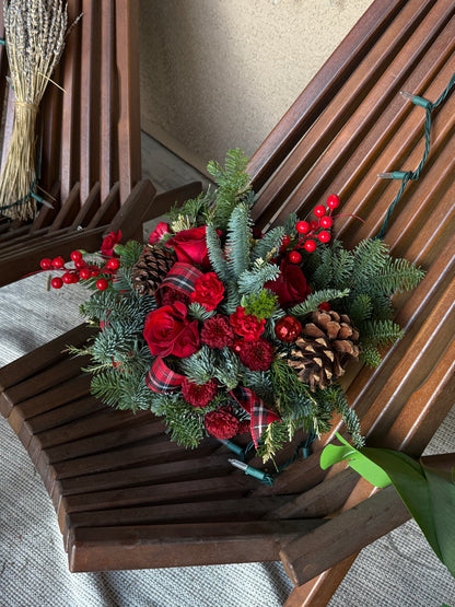 Mid-size festive red holiday centerpiece with noble fir, cedar, white pine, pinecones, and red berries on a dining table