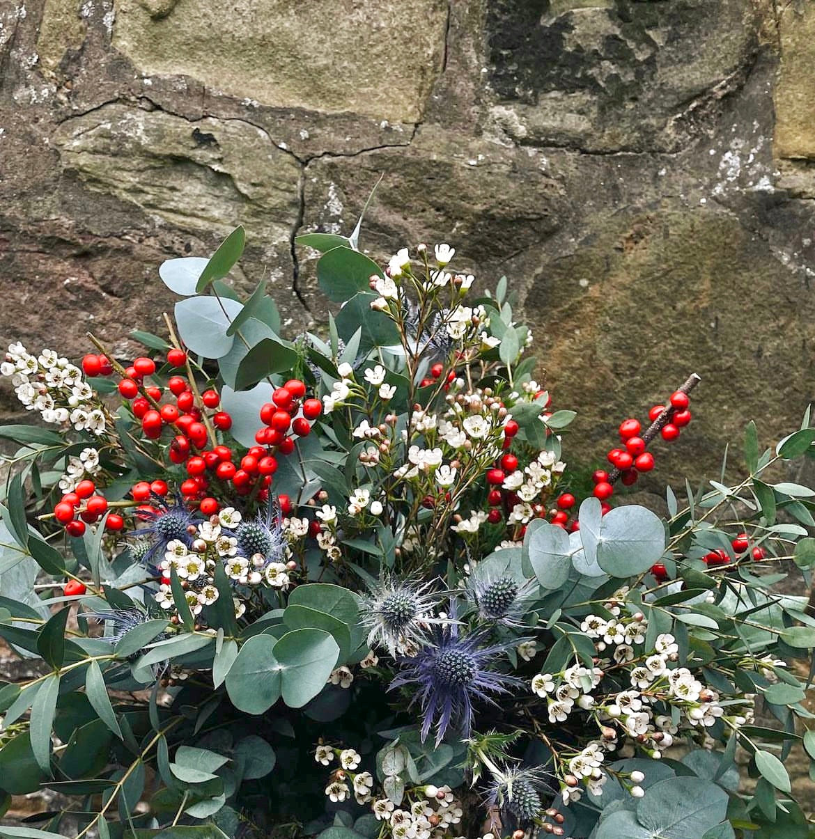 Hand-wrapped holiday bouquet with eucalyptus, berries, filler flowers, and seasonal greenery.
