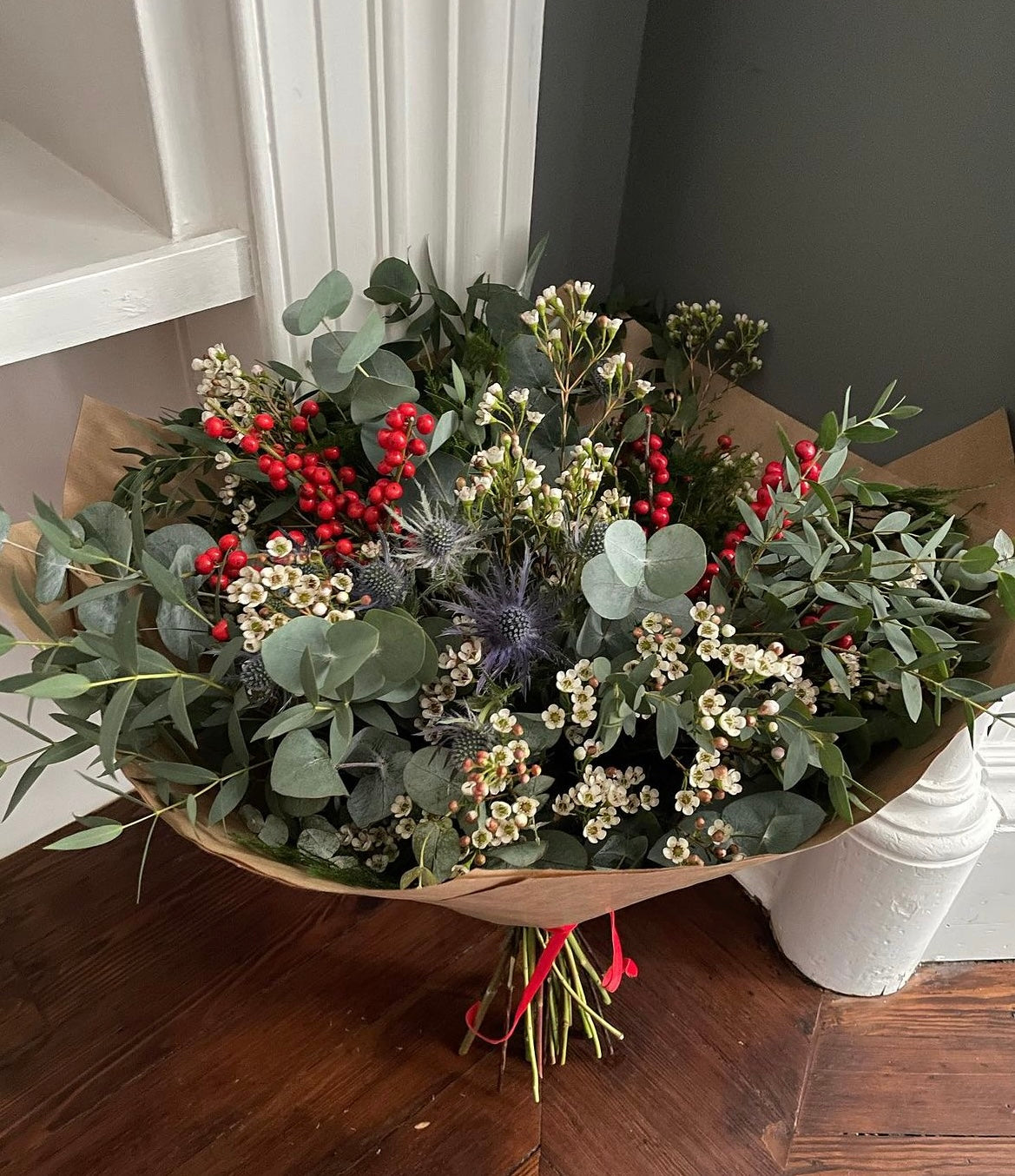 Hand-wrapped holiday bouquet with eucalyptus, berries, filler flowers, and seasonal greenery.
