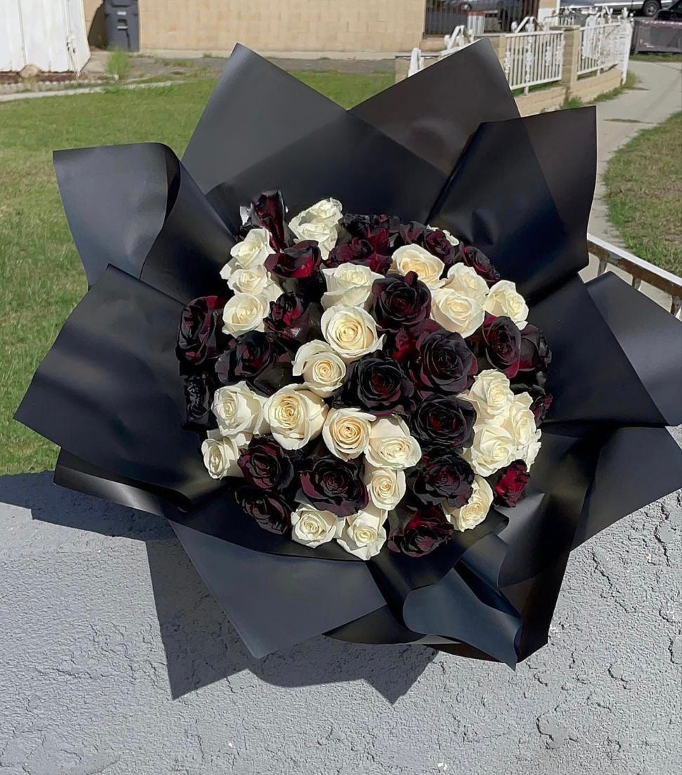 Halloween themed bouquet featuring black and white roses accented with spooky spider web decorations, black paper wrapped.