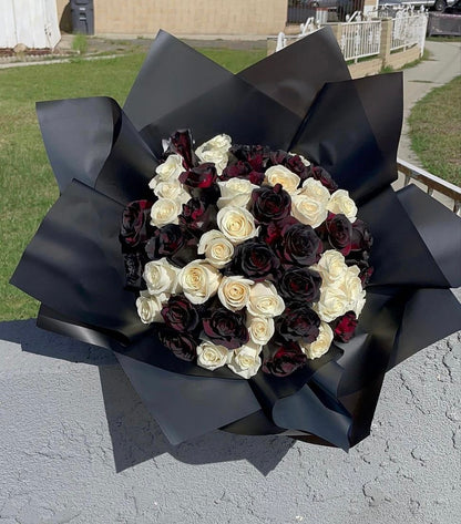 Halloween themed bouquet featuring black and white roses accented with spooky spider web decorations, black paper wrapped.