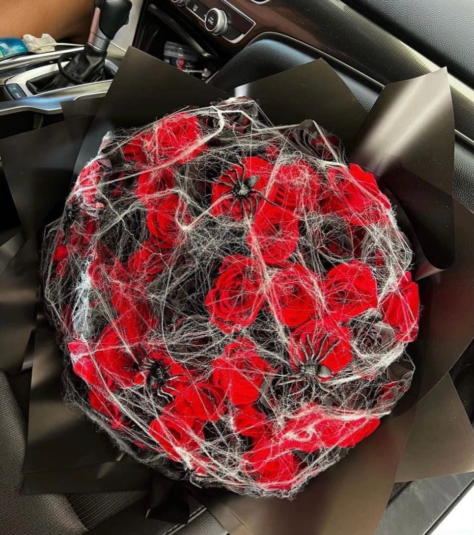 Maroon and black roses arranged in a dramatic and elegant bouquet with spider web