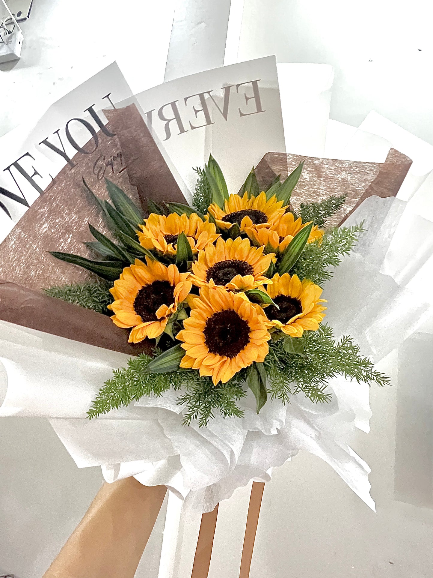 Fresh sunflower arrangement with seasonal greens and rustic wrapping.
