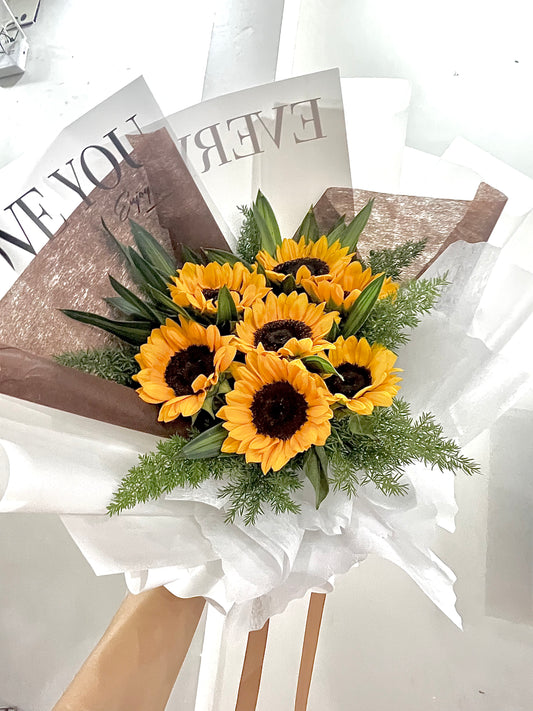 Fresh sunflower arrangement with seasonal greens and rustic wrapping.