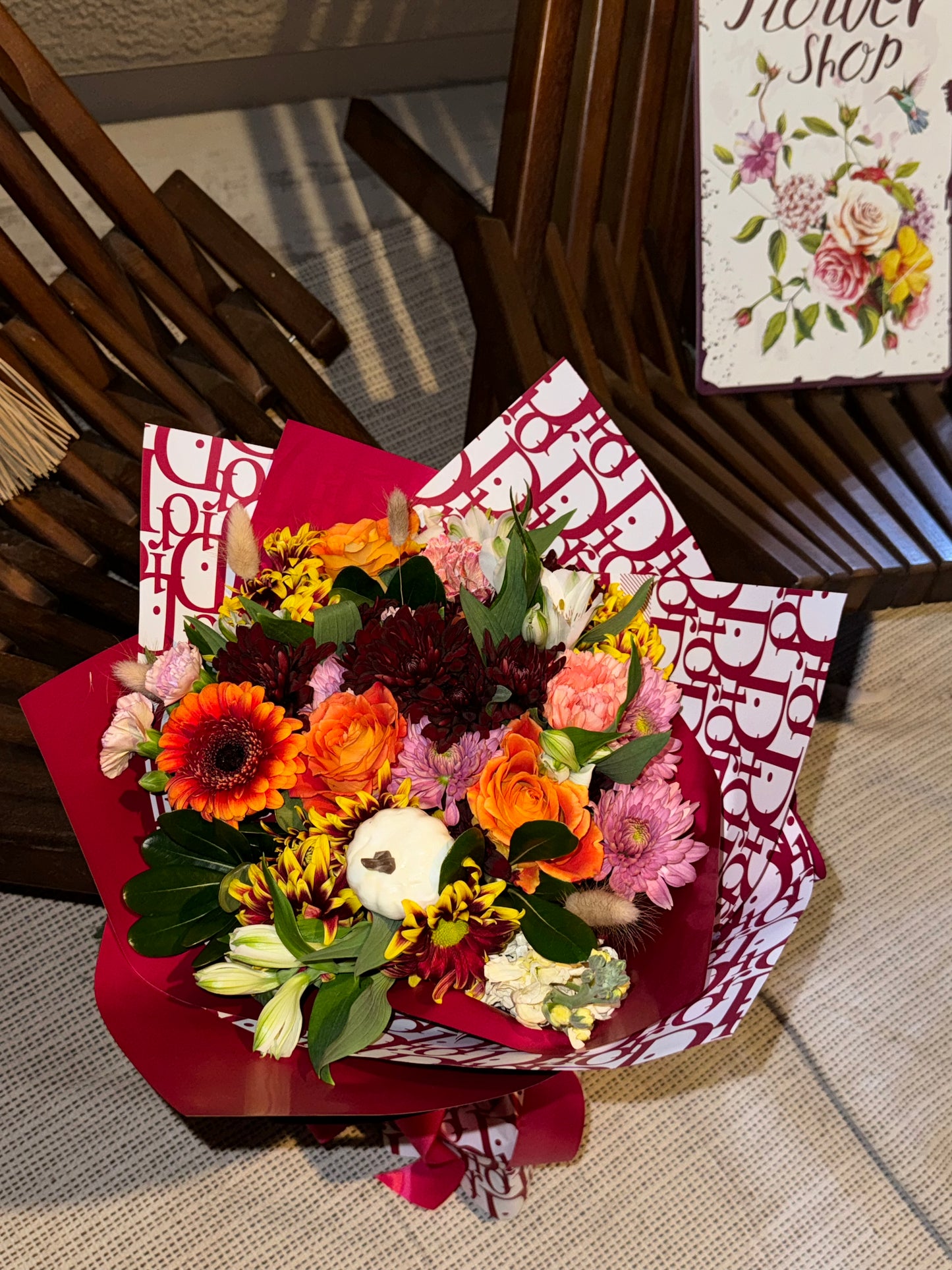 Fall bouquet with yellow, orange, red, and brown seasonal blooms, wrapped with filler, greenery, and fall decoration