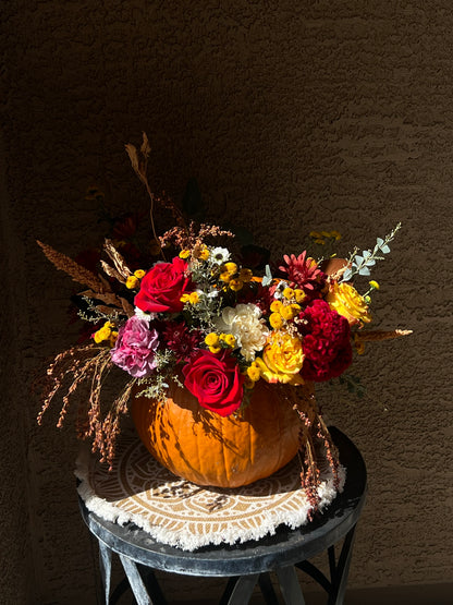 Surprised Pumpkin Centerpiece featuring fresh flowers and preserved decorations arranged inside a unique pumpkin. Available in standard, deluxe, and premium sizes with varying flower stems and higher-value blooms.