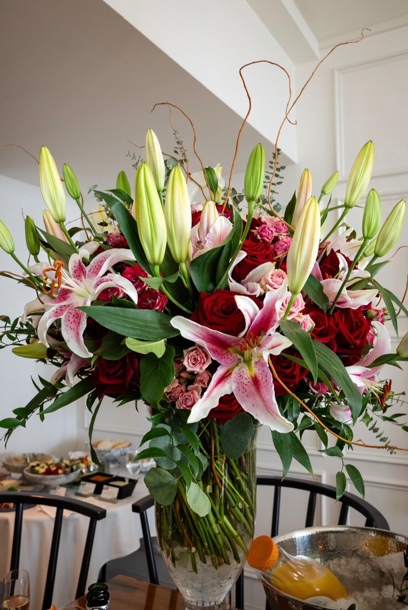 Bouquet of flowers with red roses and white lilies in a vase on a table.