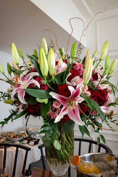 Bouquet of flowers with red roses and white lilies in a vase on a table.