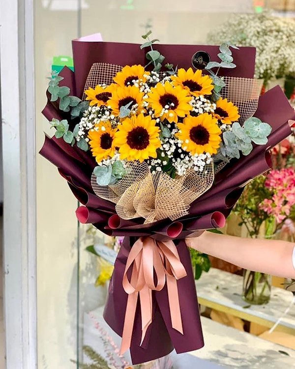 Hand-wrapped sunflower bouquet with greenery and filler flowers.
